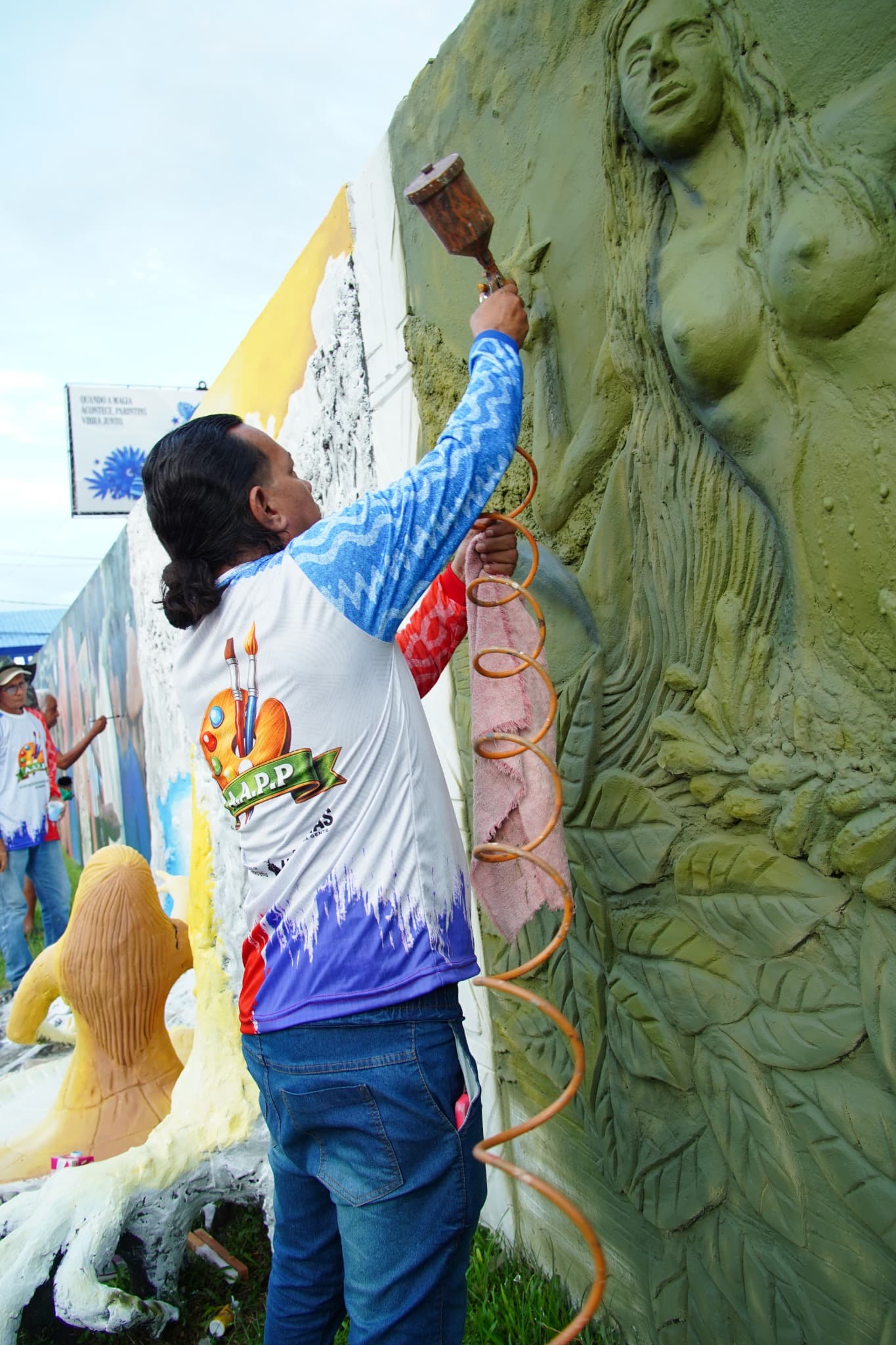 Artista aplicando pintura em escultura